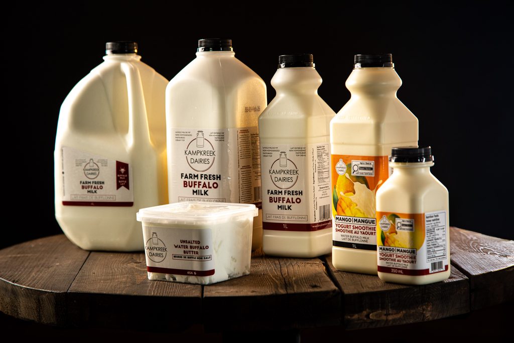 Kampkreek Dairies water buffalo milk, butter, and mango yogurt smoothie products displayed on a wooden table